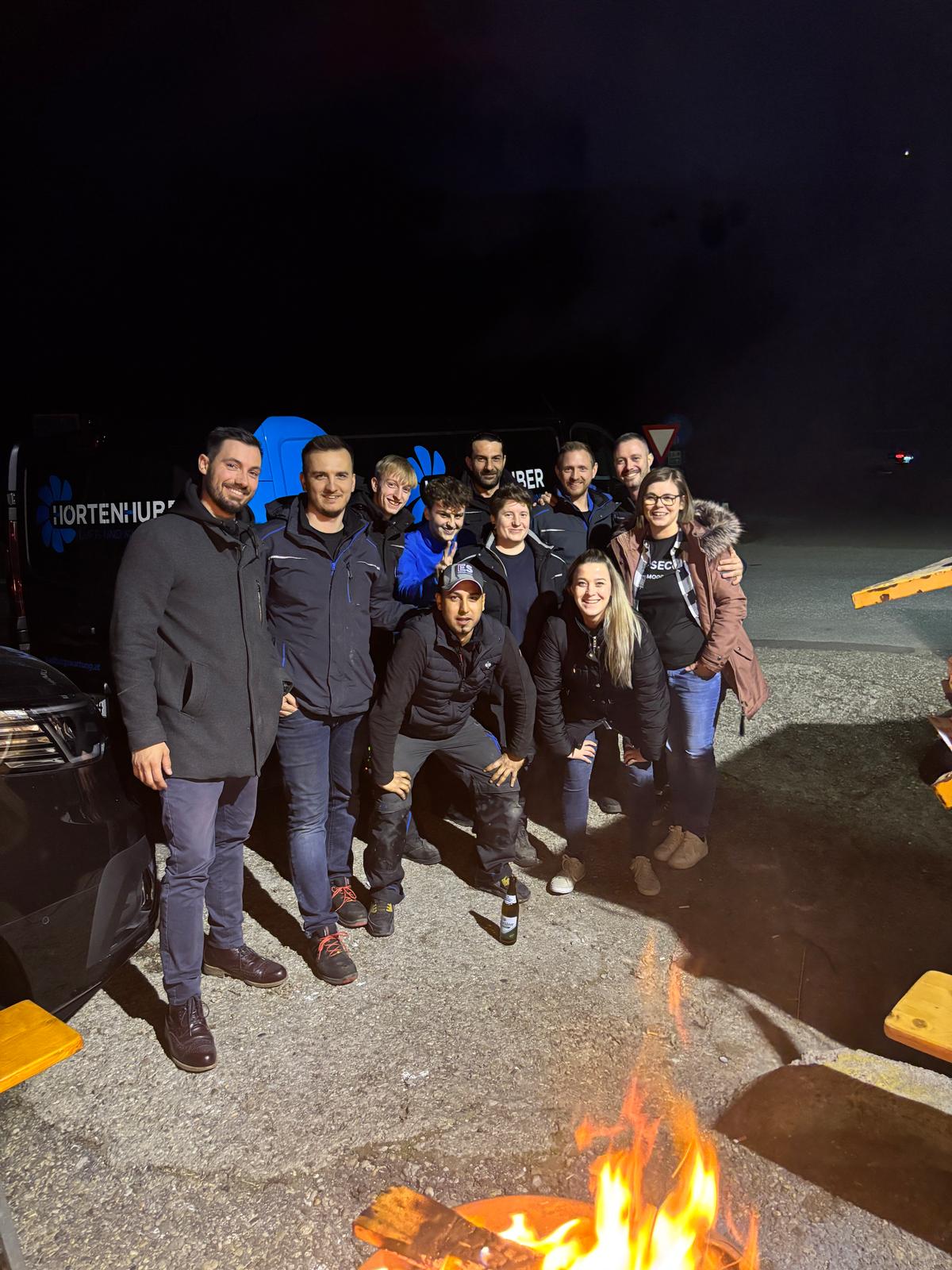 Teamfoto bei einem gemeinsamen Abend am Lagerfeuer.